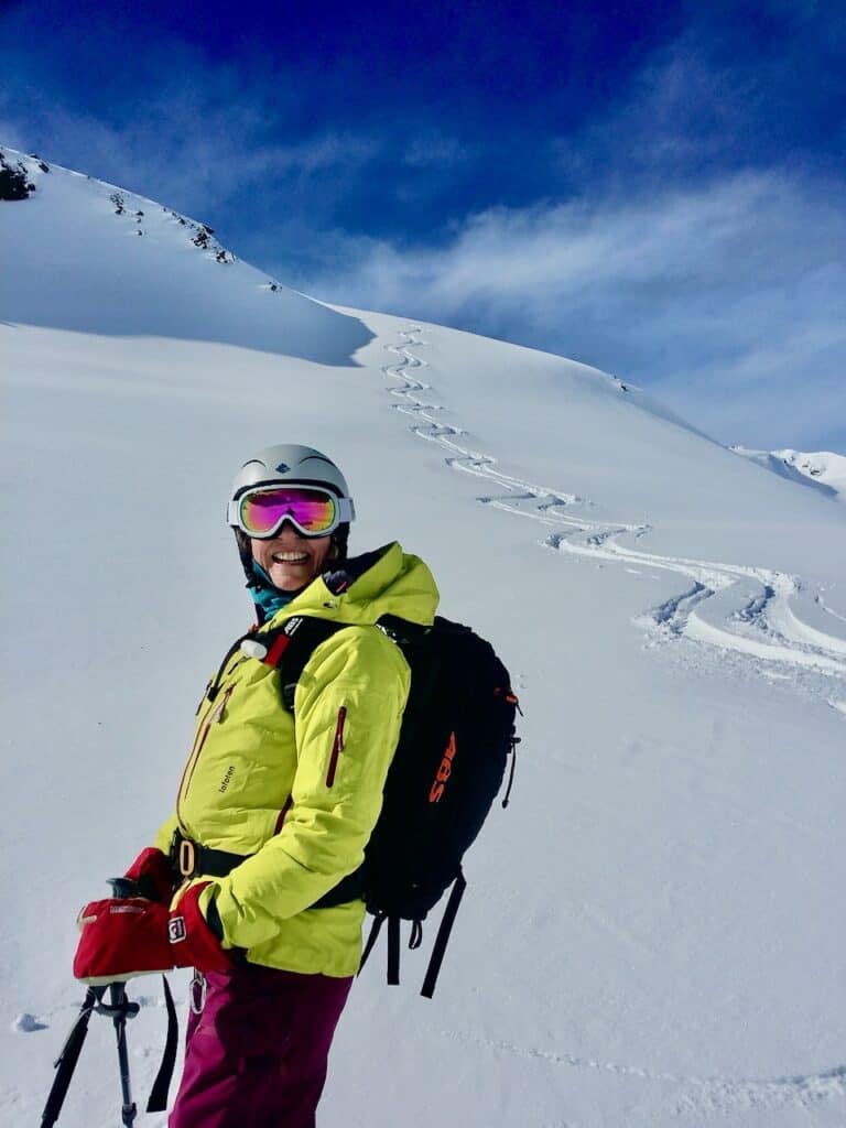 Skifahrerin mit gelber Jacke Abs Rucksack mit Spuren im Pulverschnee. Skitouren am Arlberg